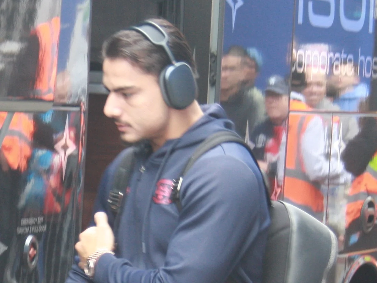 Jusef Erabi i mörkblå huvtröja och hörlurar på väg in till en match i september 2026